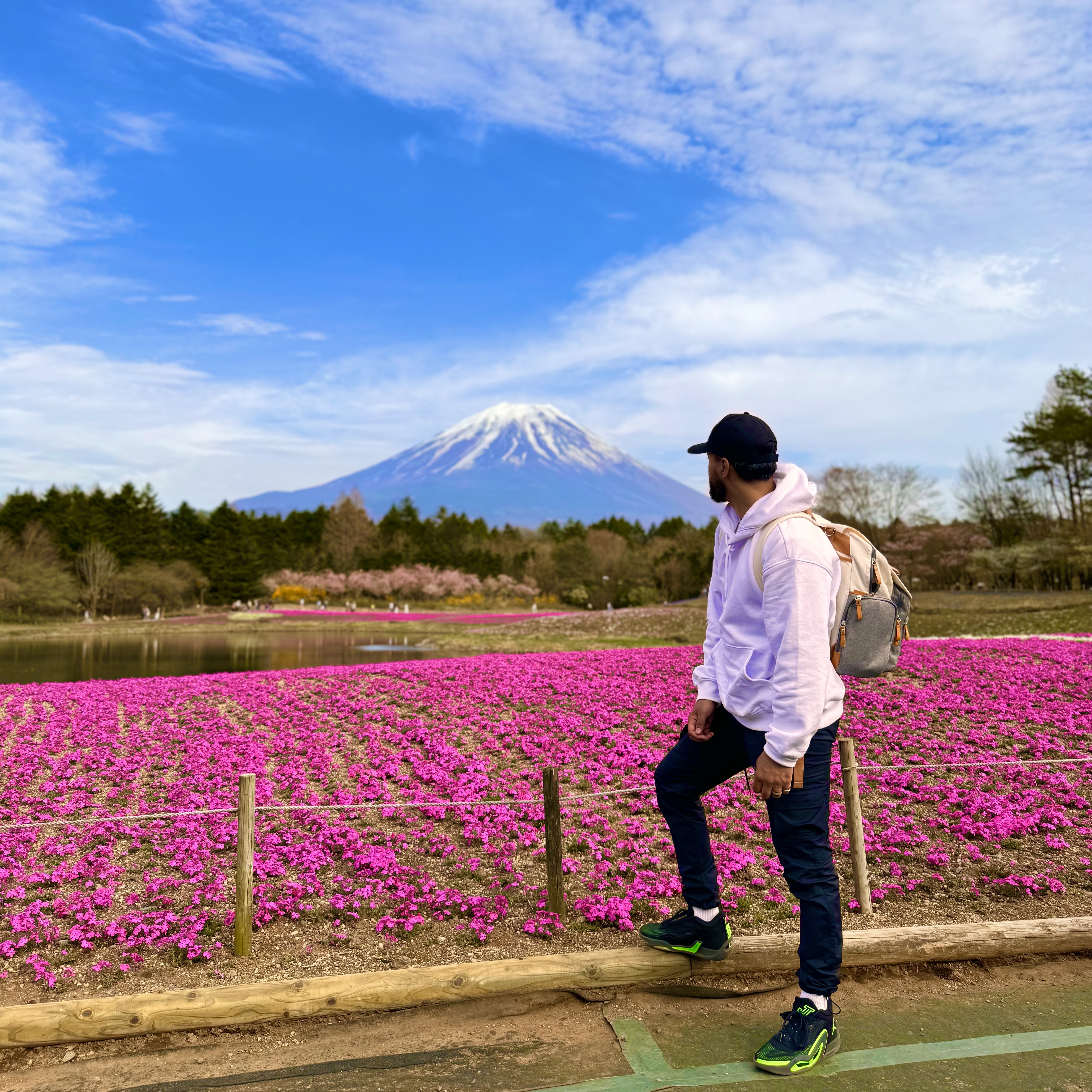 Zeeshan in the foreground looking back at Fuji Mountain in the background while surrounded by a bed of flowers